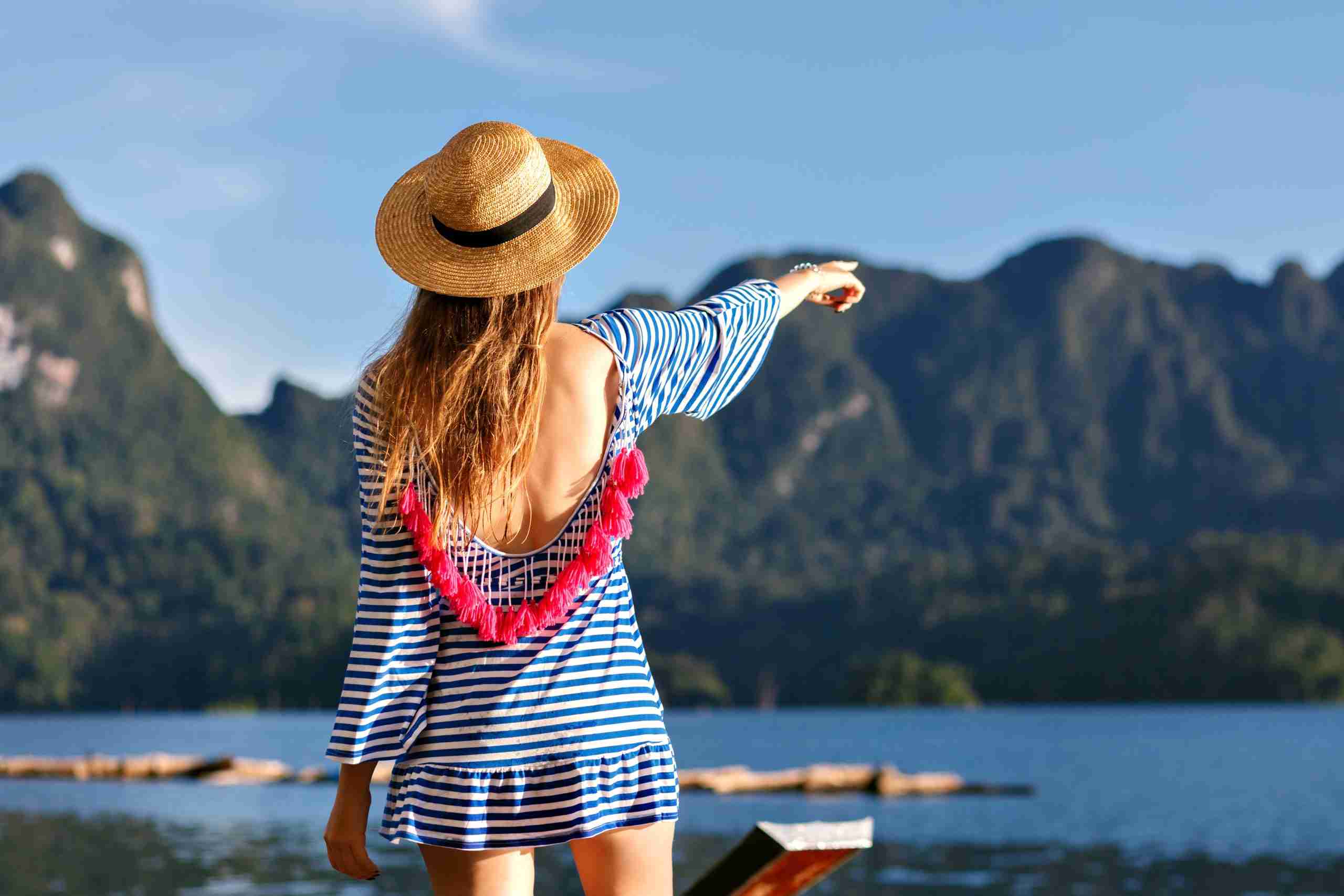 young pretty blonde woman with long hairs wearing vintage hat bright sexy trendy dress looks mountains lake show her hand amazing summer adventures scaled